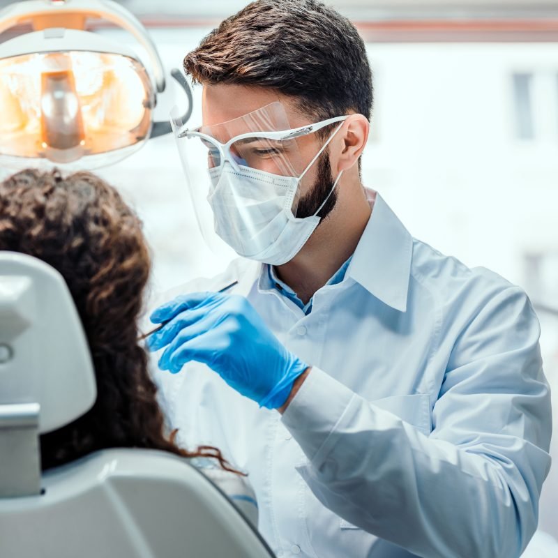 Dentist working in dental clinic with patient in the chair.